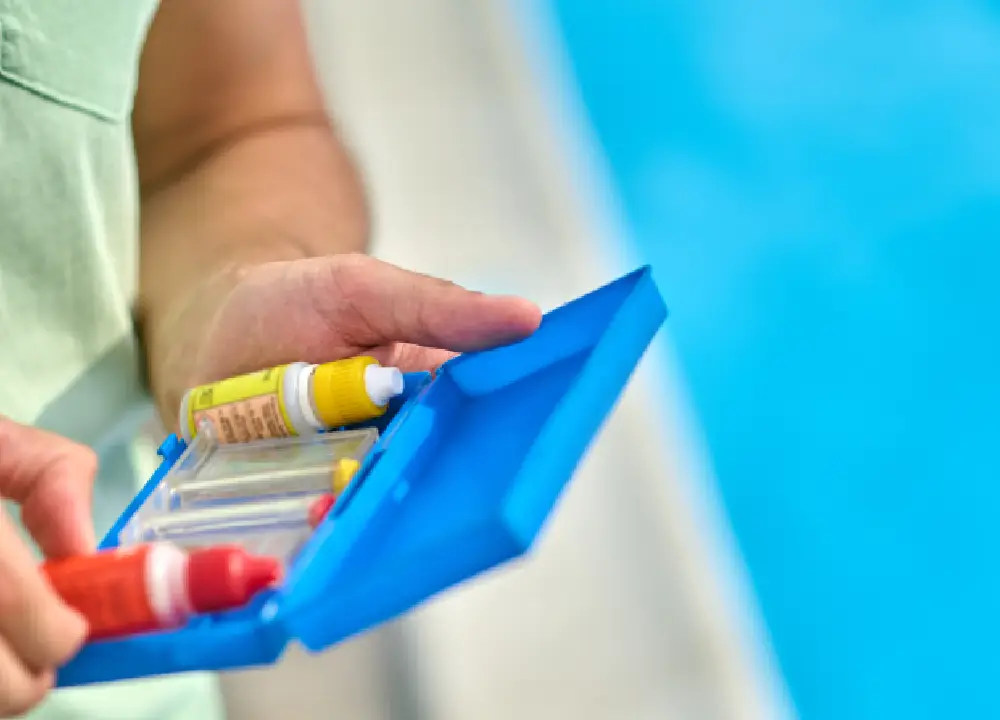 A pool water testing kit being used to check chemical levels in a swimming pool.